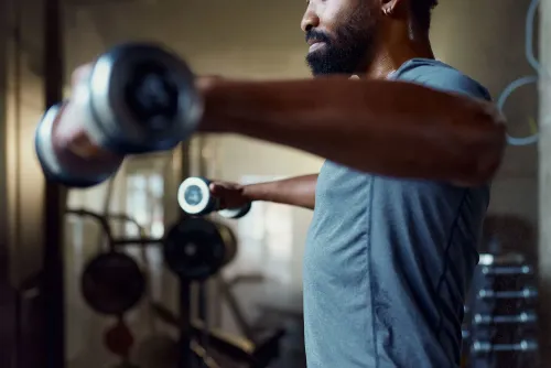 رجل يمارس تمارين القوة في صالة رياضية، مما يعكس روح مبادرة "الإغلاق العظيم" لتحسين اللياقة البدنية وتحقيق الأهداف الصحية.