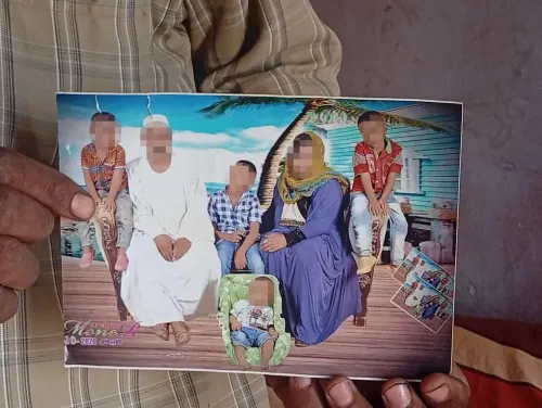 يد يحمل صورة عائلية لخمسة أطفال وامرأة ورجل، تعبير عن الخسائر الإنسانية في حرب الطائرات المسيّرة في مدينة الأبيض السودانية.
