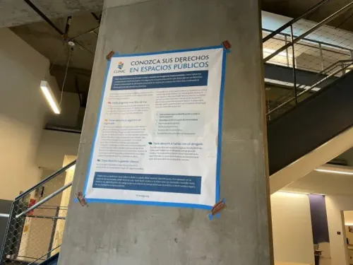 ملصق يوضح حقوق الأفراد في الأماكن العامة، مع معلومات مهمة للمهاجرين، مثبت على جدار في مبنى حديث.