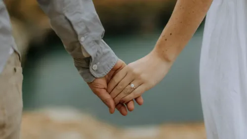 يد تحملها زوجان مع خاتم زفاف، تعكس العلاقة العاطفية والتفكير في اتفاقية ما قبل الزواج لحماية الأصول.