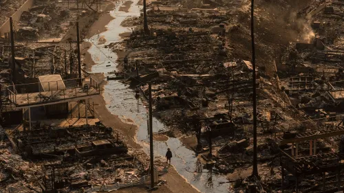 مشهد لمدينة مدمرة بعد حرائق الغابات، مع دمار شامل للمباني والطرق. تظهر آثار الكارثة على المنازل وتأثيرها على التأمين.