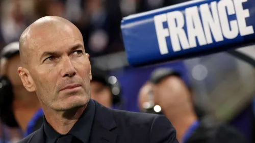 زين الدين زيدان بزي رسمي يقف على مقاعد بدلاء منتخب فرنسا خلال مباراة دوري الأمم الأوروبية أمام إيطاليا في استاد دو فرانس.