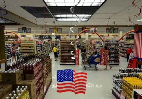 متجر بقالة داخلي يظهر أرفف مليئة بالمنتجات، مع زبائن يتسوقون، وديكورات احتفالية تتضمن علم الولايات المتحدة.