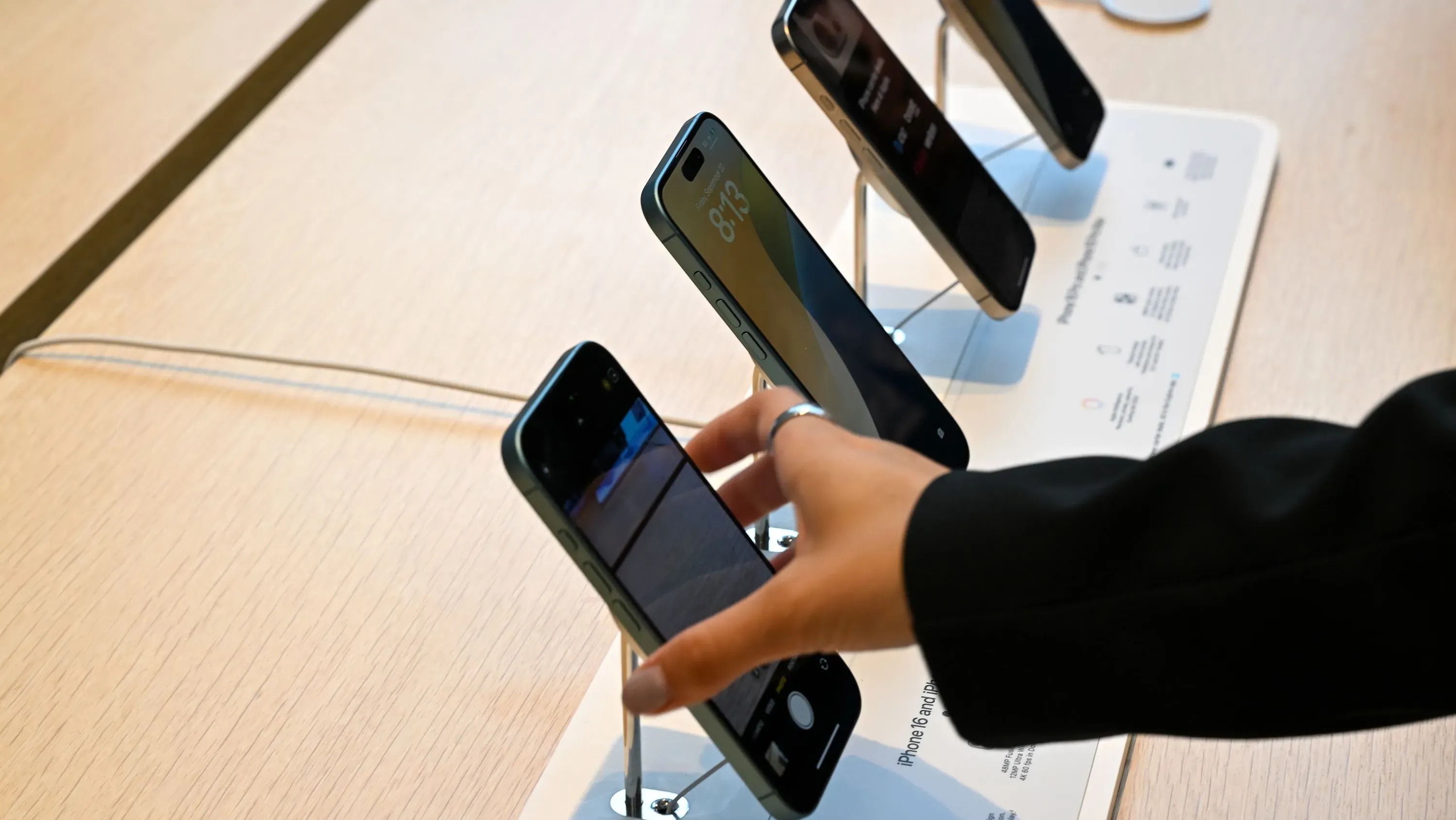 هواتف ذكية معروضة في متجر، حيث تُظهر اليد تجربة الاستخدام، في سياق إعفاء الإلكترونيات المستوردة من التعريفات الجمركية في الولايات المتحدة.