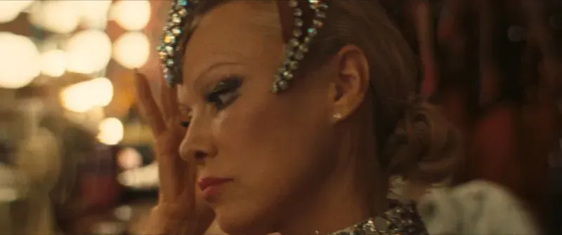 امرأة تتأمل في مرآة مع تسريحة شعر أنيق ومكياج لامع، تعكس أجواء السينما والفنون. تتعلق الصورة بترشيحات جوائز الأوسكار.