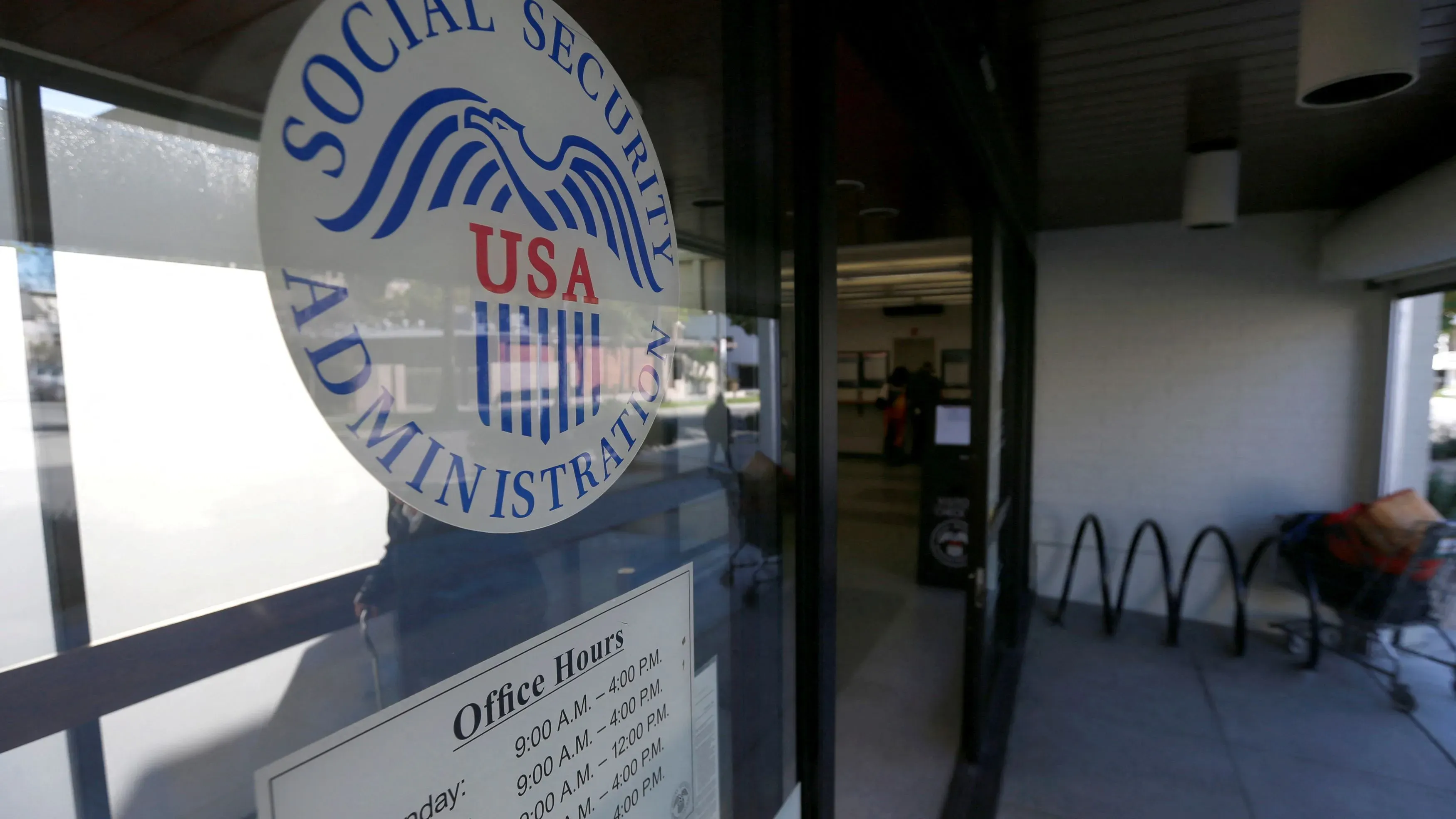 مدخل مكتب إدارة الضمان الاجتماعي في الولايات المتحدة، مع لافتة توضح ساعات العمل والمعلومات الأساسية عن الخدمات المقدمة.
