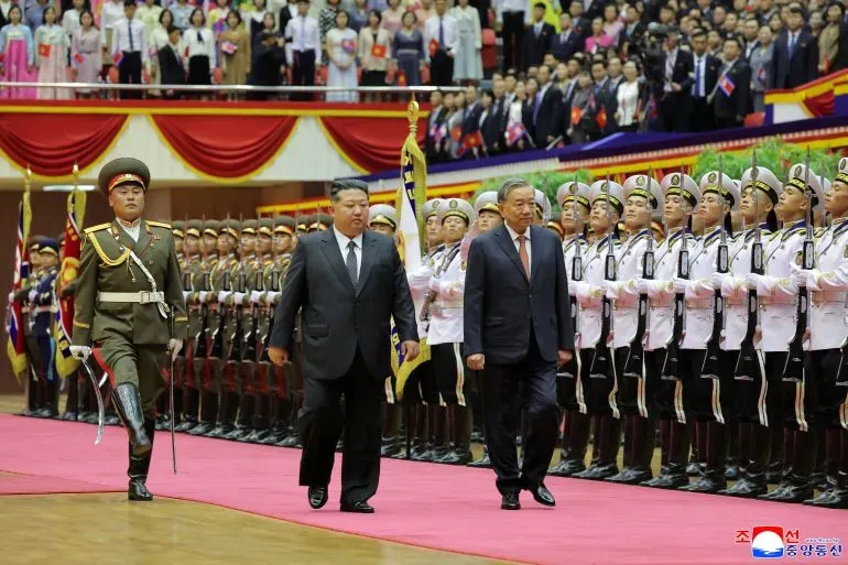 كيم جونغ أون يسير مع ضيوف خلال احتفالات الذكرى الثمانين لحزب العمال الكوري، وسط حشد من الجنود والمشاهدين في استاد بيونغ يانغ.