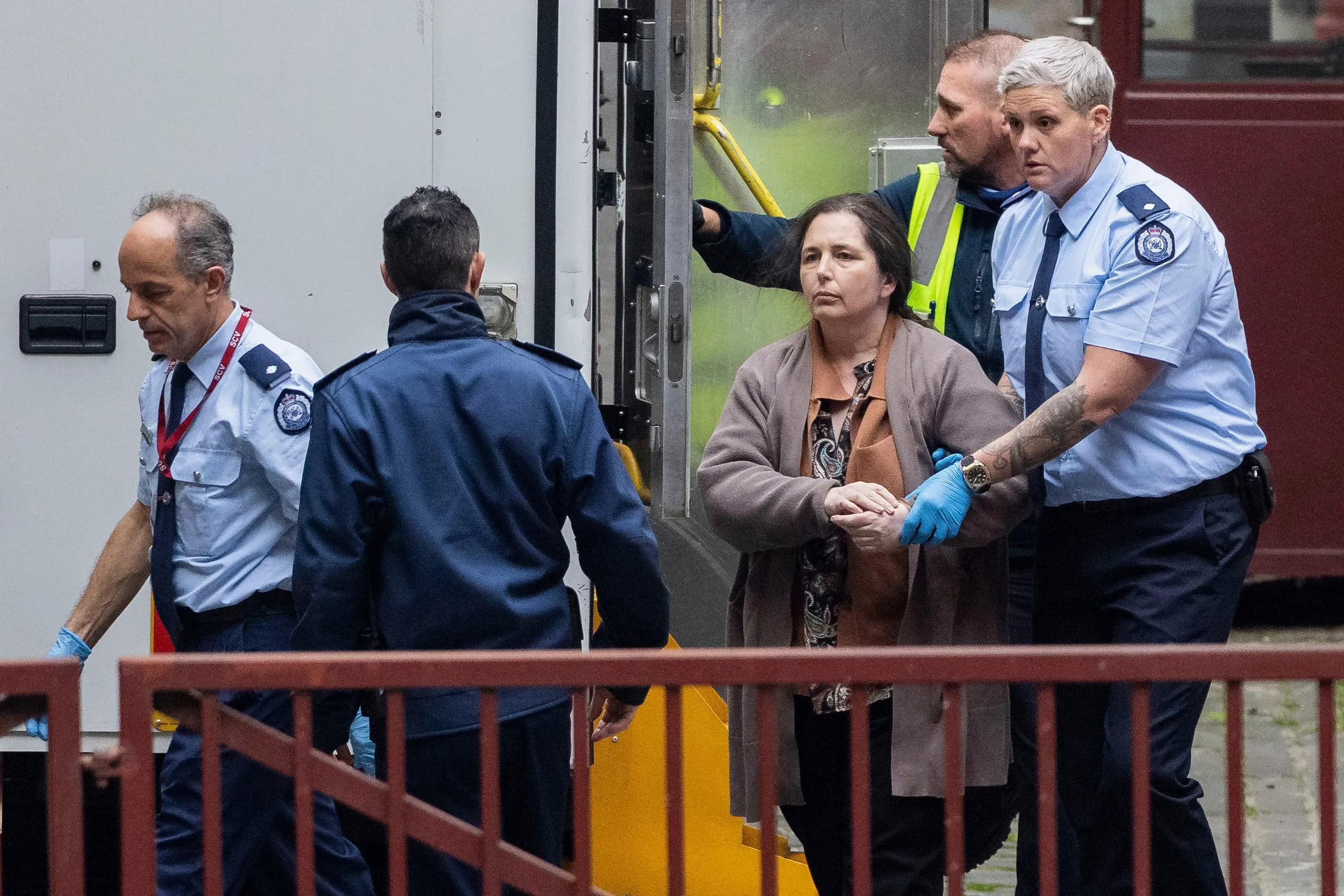 إيرين باترسون، المدانة بقتل ثلاثة أشخاص، تُنقل من سيارة الشرطة إلى المحكمة، وسط حضور أمني مكثف.