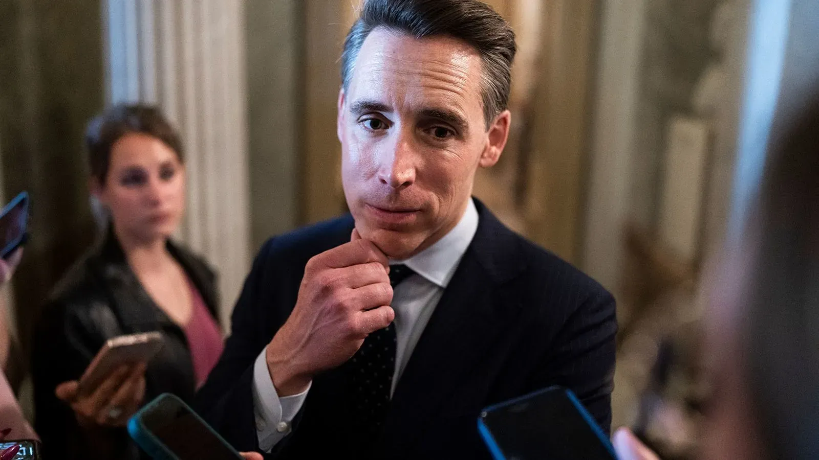 السيناتور جوش هاولي يتحدث إلى الصحفيين في مبنى الكابيتول، مع تعبير جاد، وسط أجواء سياسية مشحونة حول قبول طائرة قطرية كهدية.