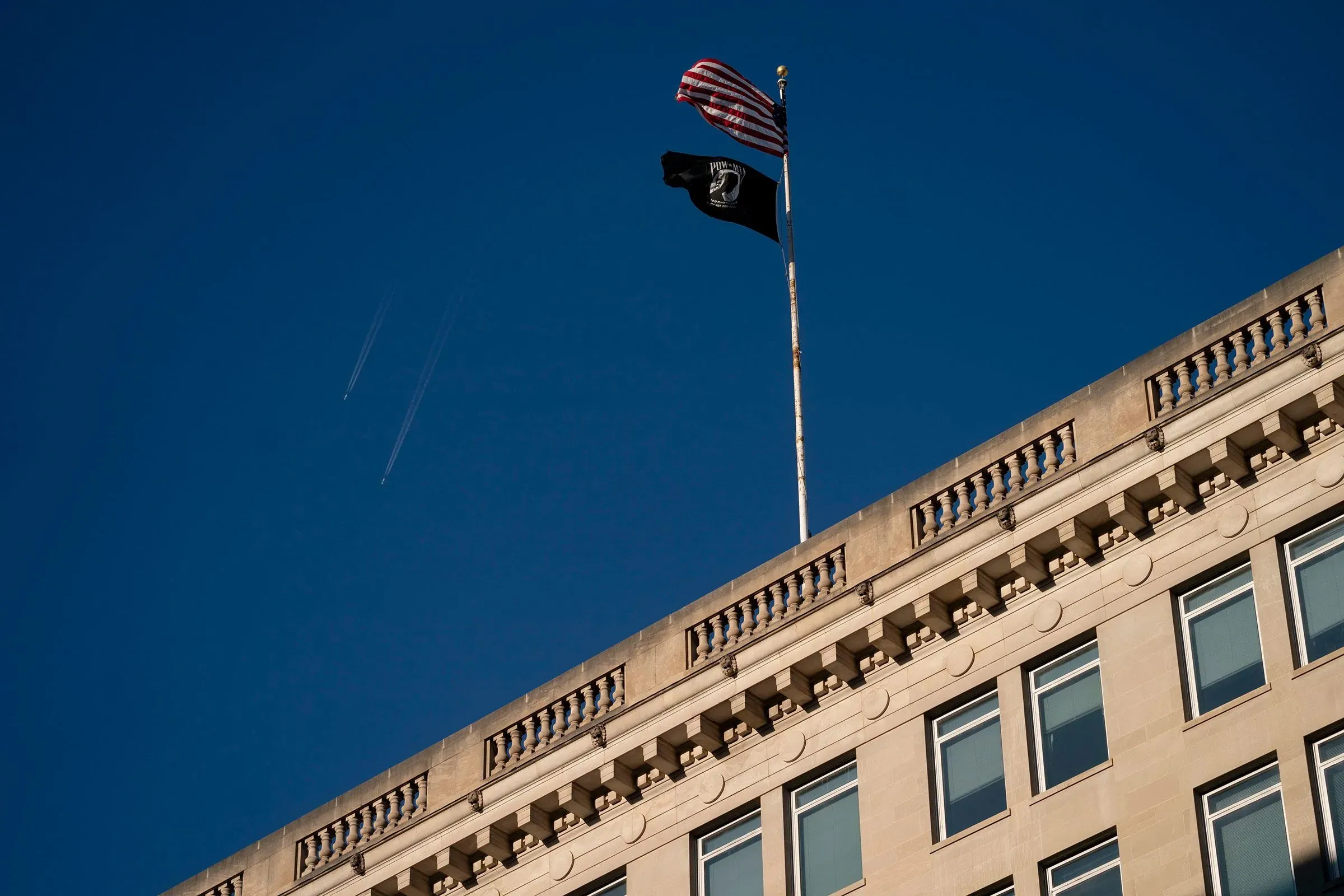 علم أمريكي يرفرف بجانب علم خاص بالمحاربين القدامى فوق مبنى، يعكس قضايا الصحة النفسية للمحاربين.