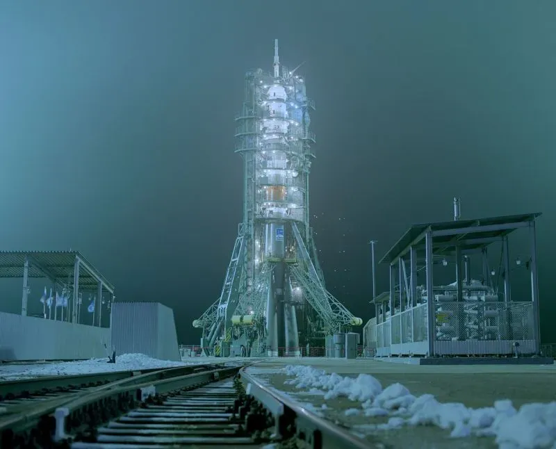 برج إطلاق صواريخ مضاء في الظلام، مع مسارات السكك الحديدية المحيطة، يمثل مشهداً تقنياً مثيراً في مجال الفضاء.