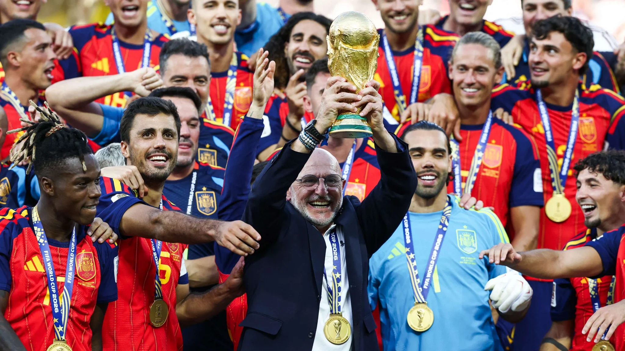 مدرب إسبانيا لويس دي لا فوينتي يرفع كأس العالم 2026 وسط لاعبي المنتخب الإسباني المحتفلين باللقب في نيو جيرسي.