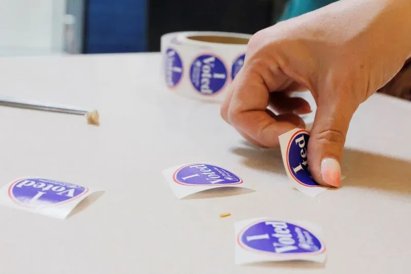 ملصقات "صوتت" تُظهر يدًا تلتقط واحدة من بين عدة ملصقات، في سياق فعالية انتخابية في ولاية كارولينا الجنوبية.