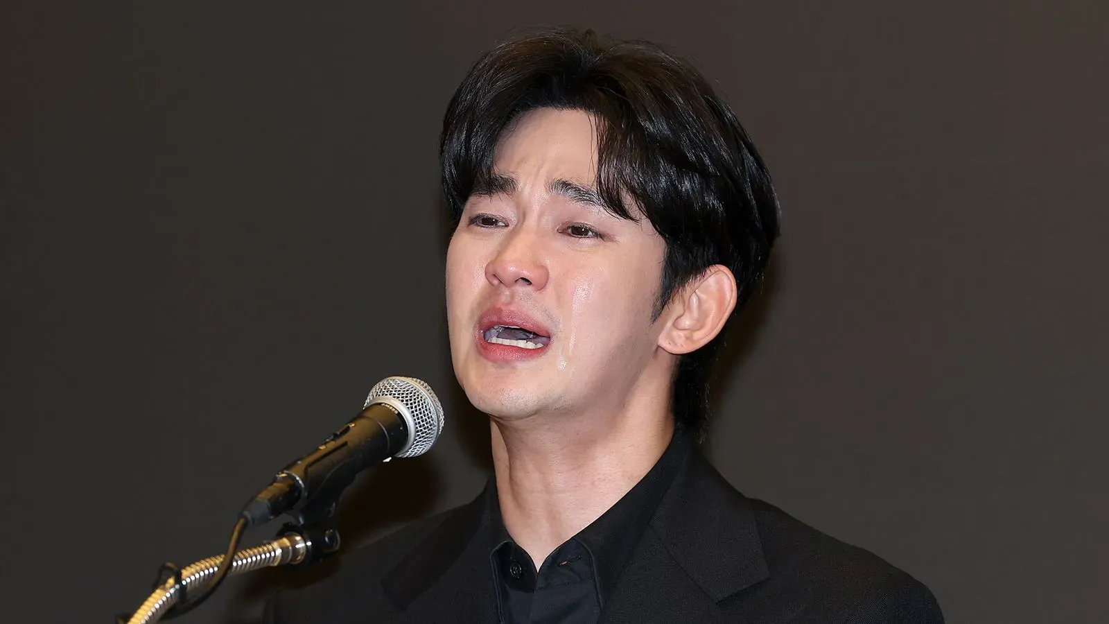 كيم سو هيون يتحدث في مؤتمر صحفي، معبرًا عن مشاعره بعد اتهامات تتعلق بعلاقته بكيم ساي-رون الراحلة، وسط أجواء عاطفية.