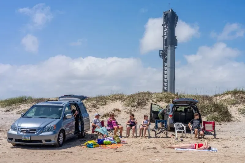 عائلة تستمتع بالشاطئ بالقرب من موقع إطلاق سبيس إكس "ستاربيس"، حيث يظهر صاروخ مرتفع في الخلفية.