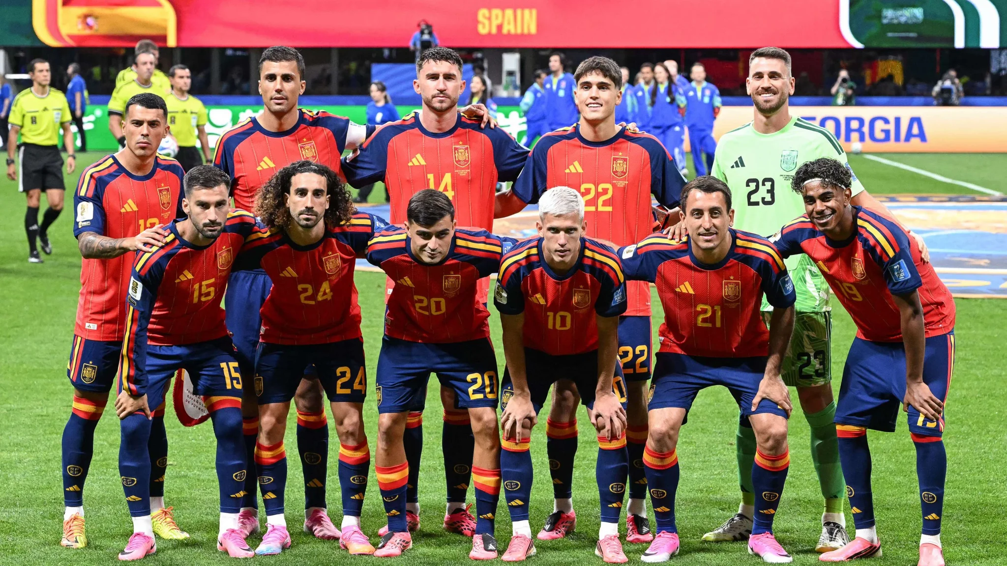 تشكيلة منتخب إسبانيا لكرة القدم في كأس العالم 2026 مرتدين الزي الأحمر والأزرق استعداداً للمباراة، مع خلفية شاشة تعرض اسم إسبانيا.