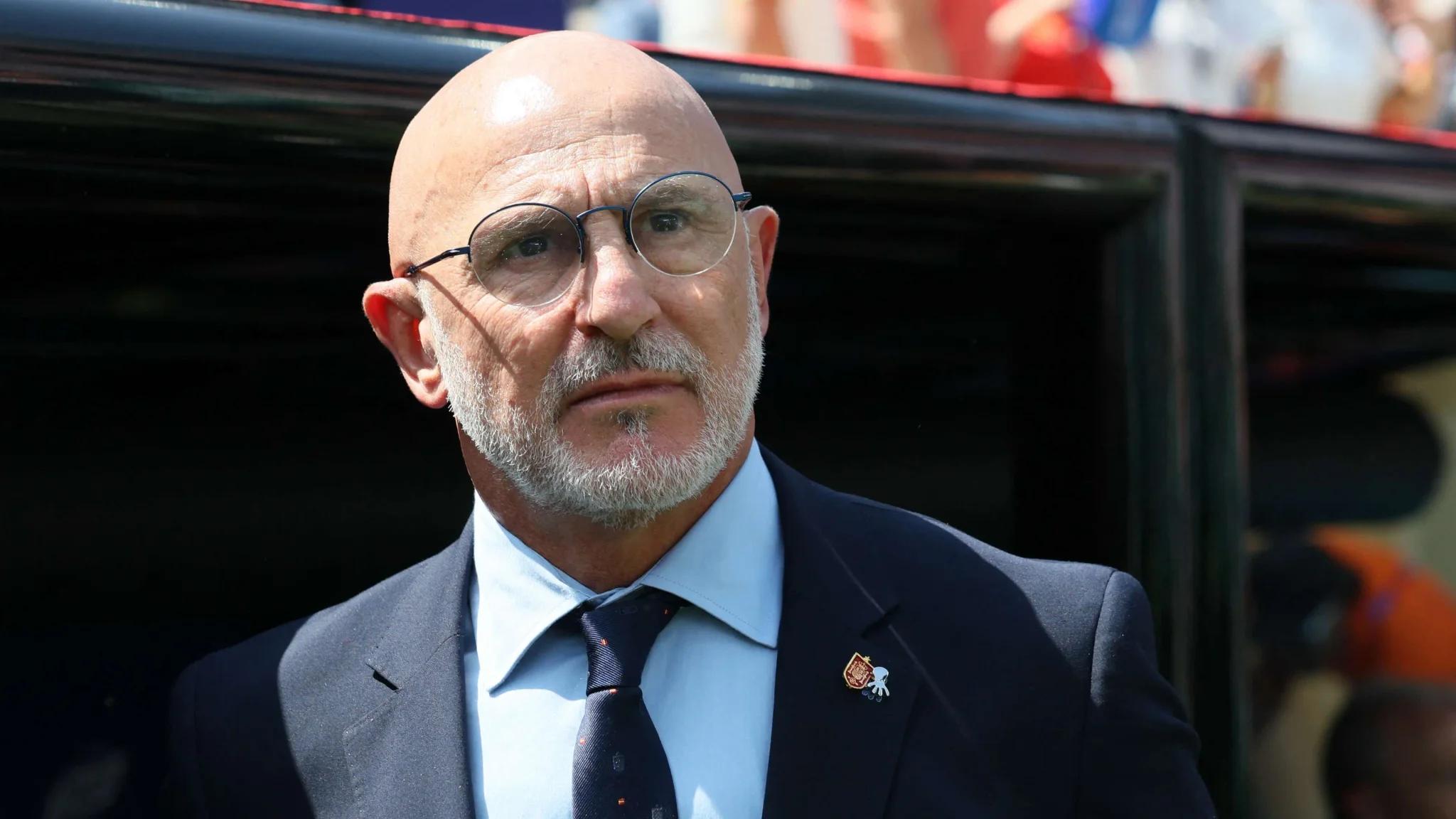 لويس دي لا فوينتي مدرب منتخب إسبانيا يرتدي بدلة رسمية ونظارات، يعبر عن ثقته بفوز لاعب إسباني بالكرة الذهبية هذا العام.
