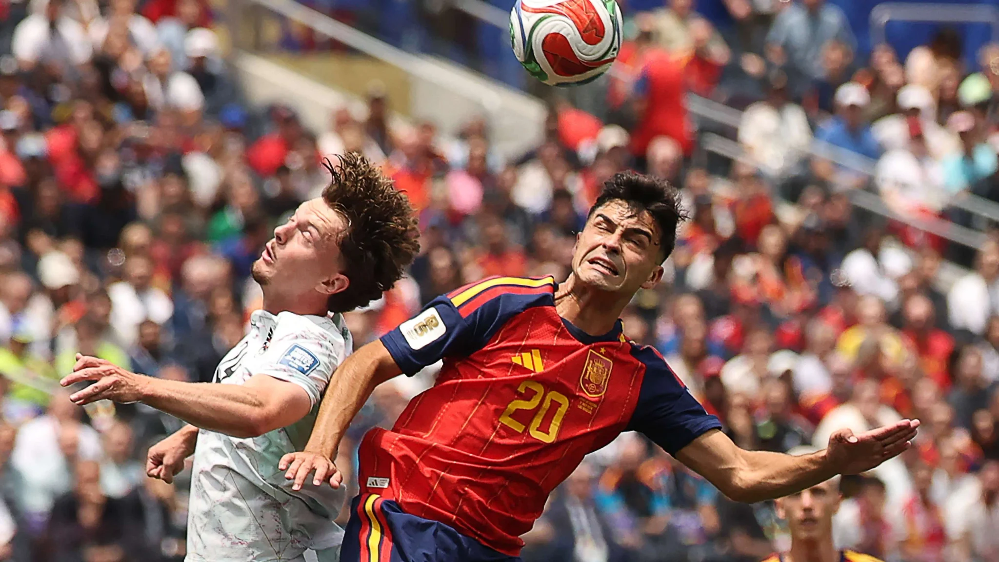 لاعب إسباني يرتدي الرقم 20 يتنافس على كرة هوائية مع لاعب من النمسا خلال مباراة كرة قدم في بطولة كأس العالم.