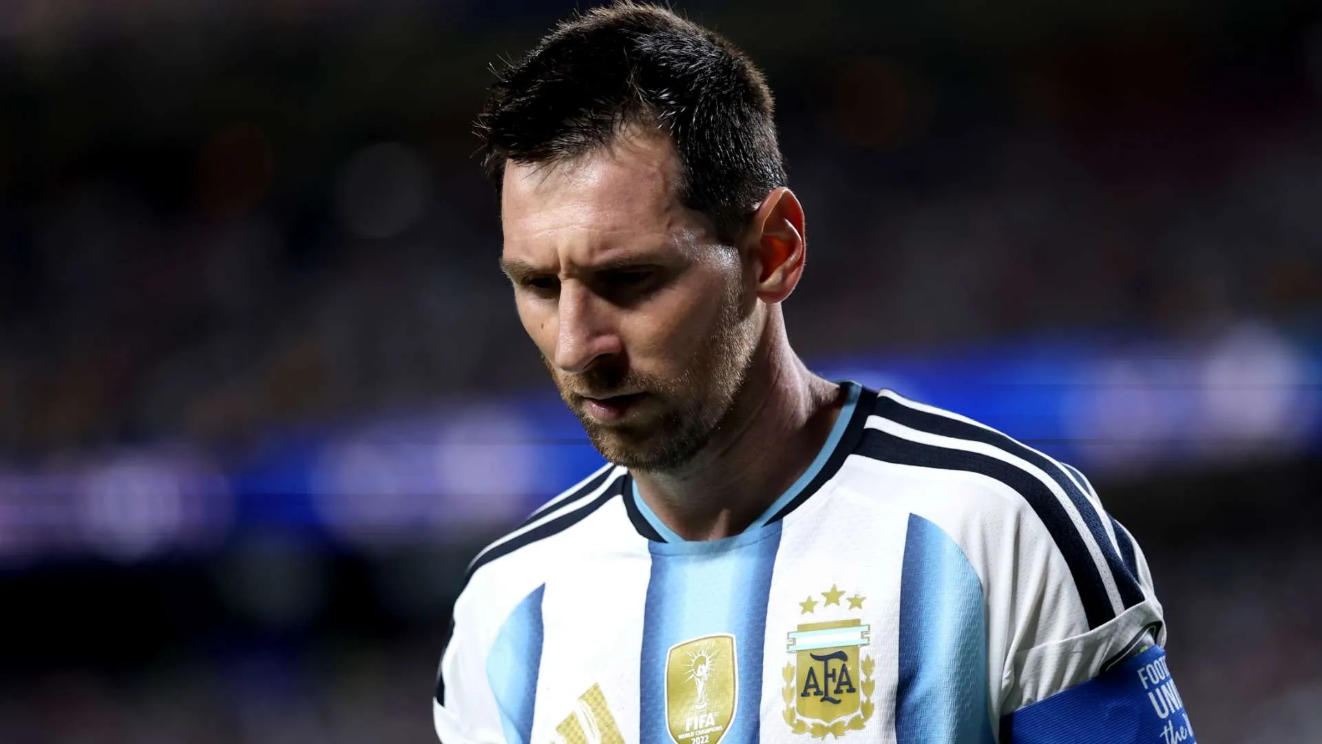 ليونيل ميسي بحزن وهو يرتدي قميص الأرجنتين بعد خسارة نهائي كأس العالم 2022، معبرة عن الألم والخيبة في المنتخب الوطني.