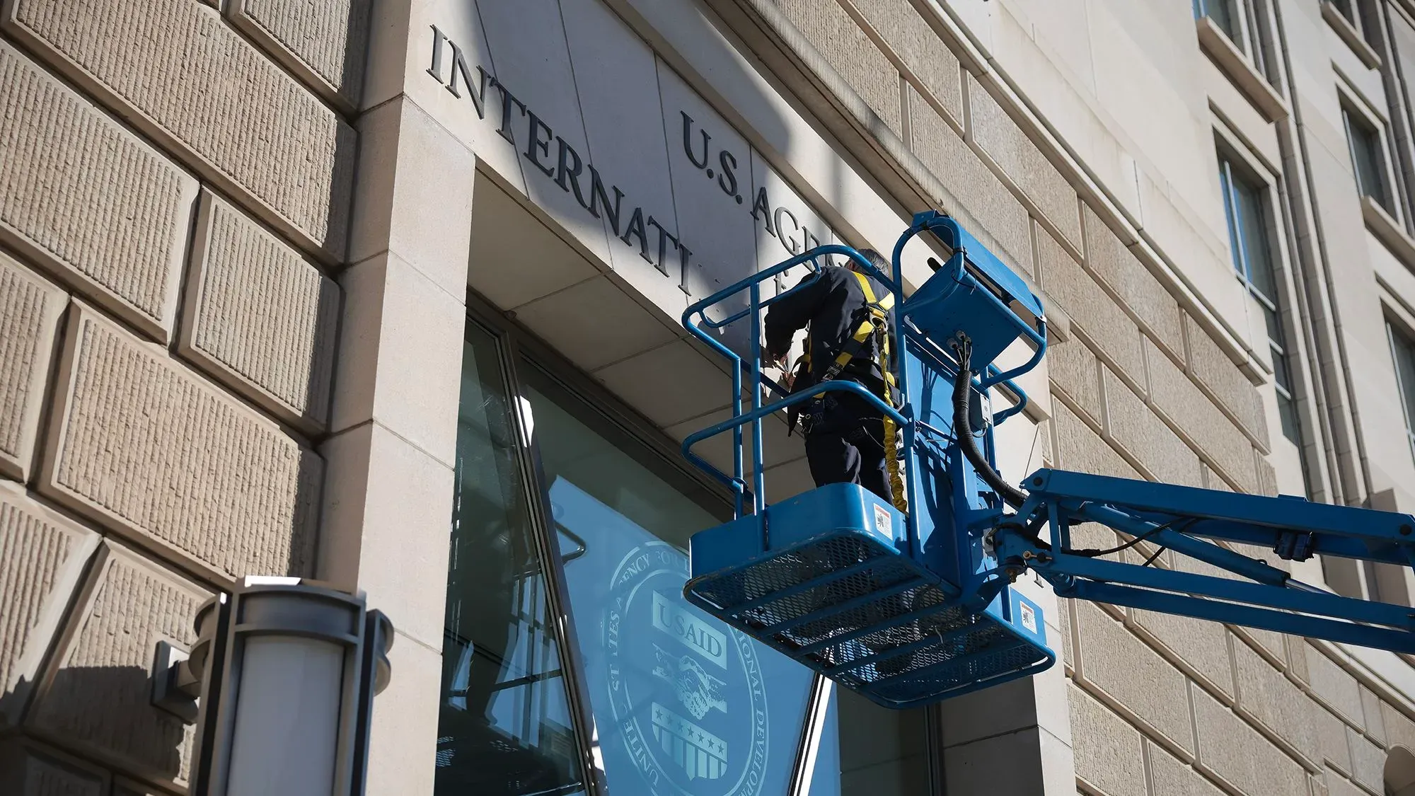 عمال يقومون بإزالة لافتة الوكالة الأمريكية للتنمية الدولية من مبنى، في سياق إعادة هيكلة الوزارة.