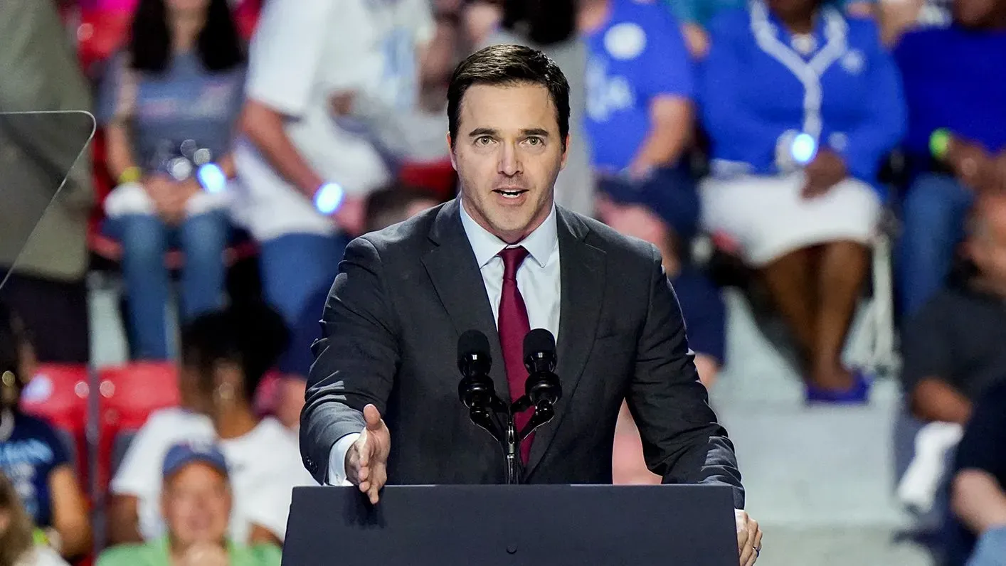 رجل يرتدي بدلة رسمية يتحدث من منصة أمام جمهور، مع وجود لافتات في الخلفية، في سياق مناقشة حول تنظيم الذكاء الاصطناعي.