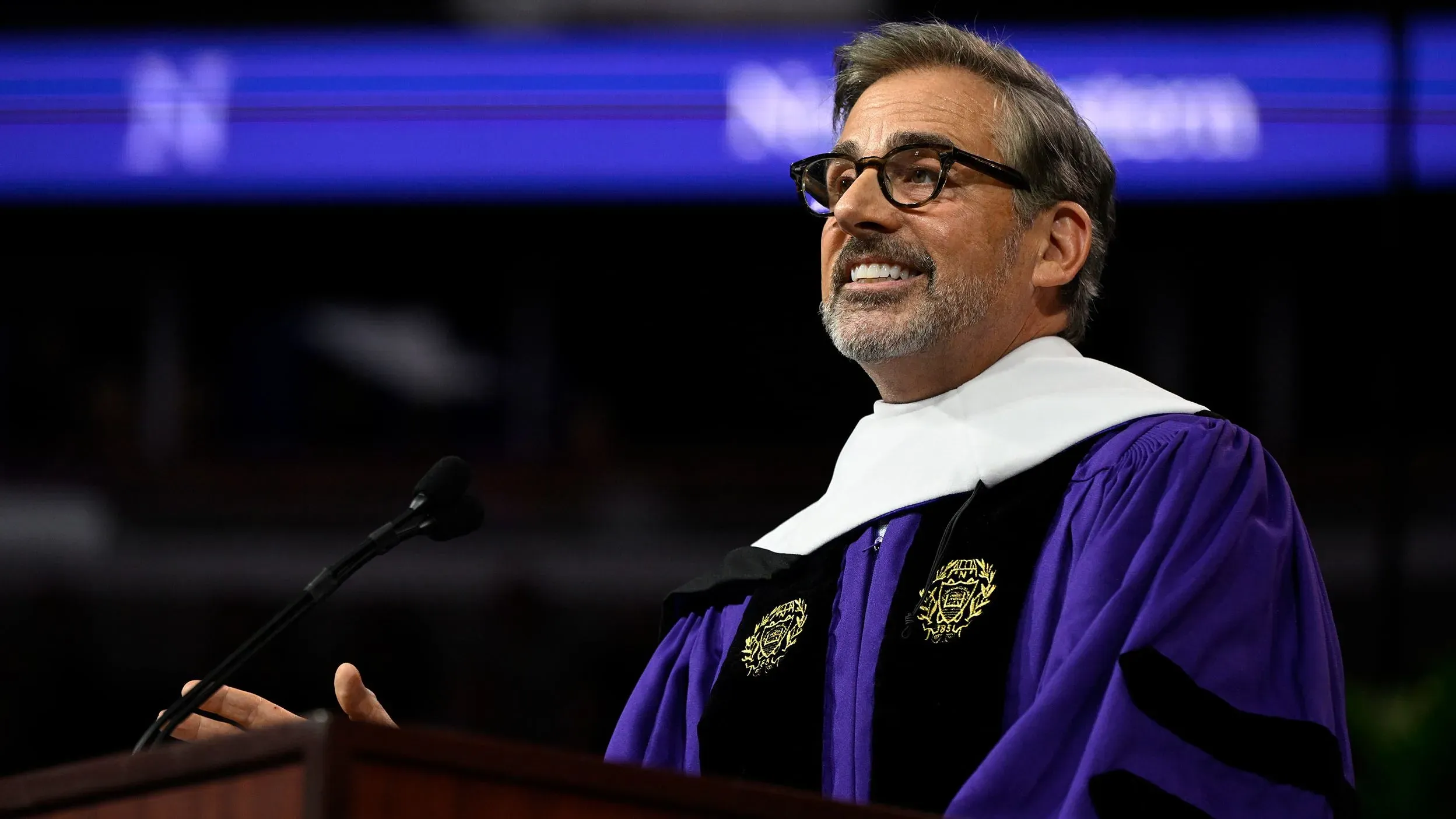 ستيف كاريل يلقي خطاب التخرج في جامعة نورث وسترن، مرتديًا رداء التخرج، مبتسمًا ويتحدث إلى الخريجين.