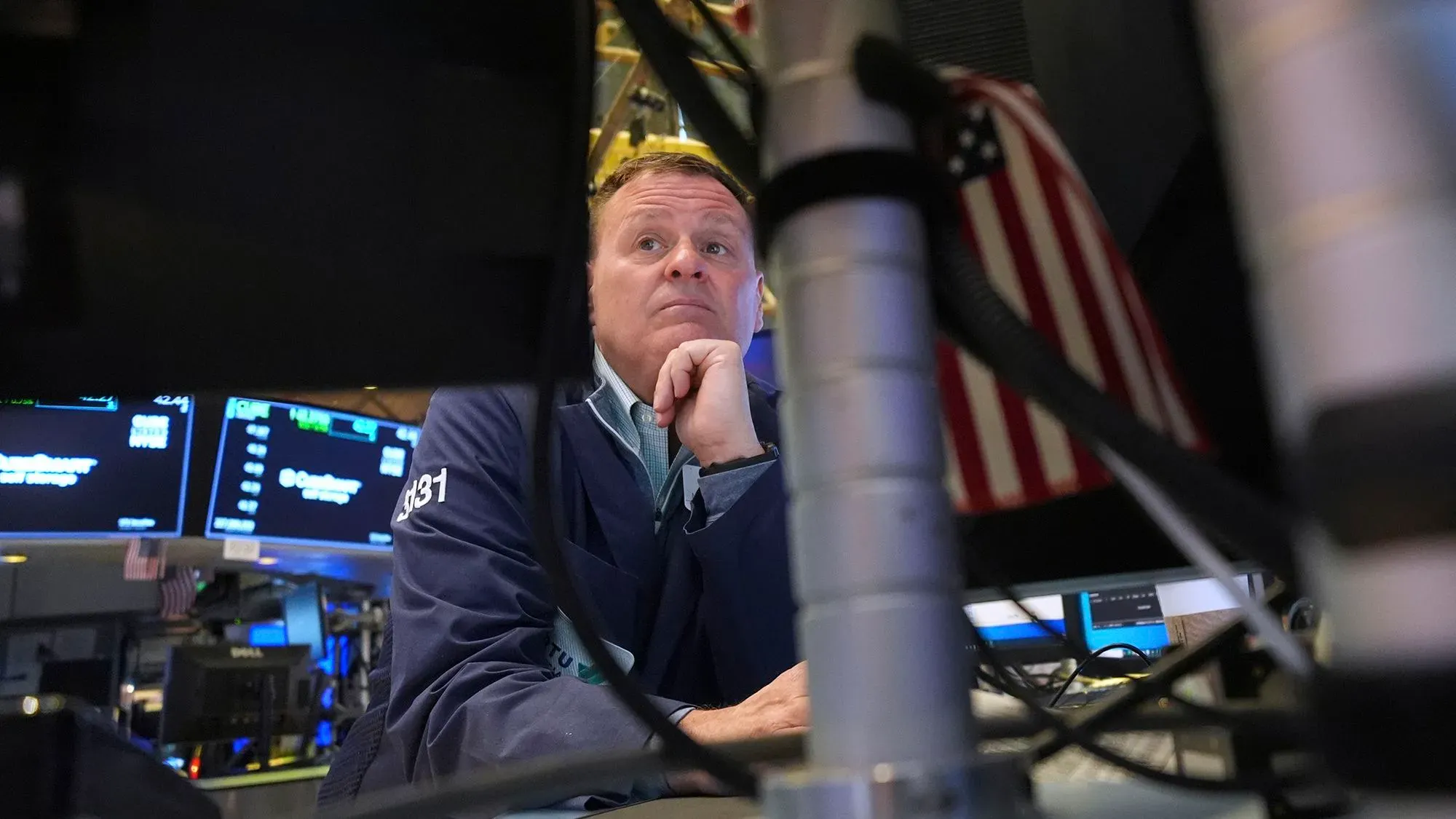 تاجر في بورصة وول ستريت يتابع الأسواق بقلق، مع وجود شاشات تعرض تراجع الأسهم بعد إعلان ترامب عن الرسوم الجمركية.