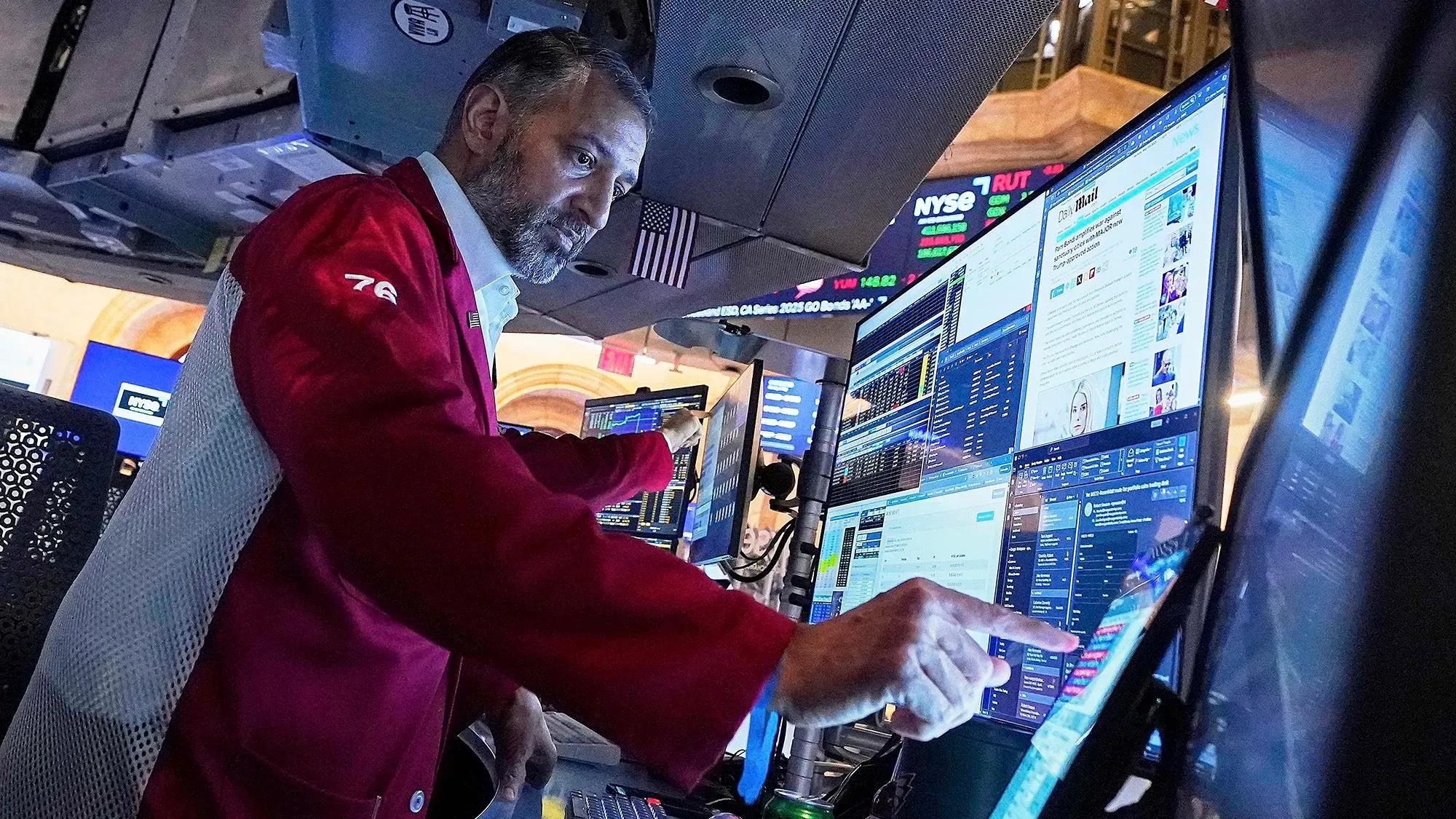 متداول في بورصة نيويورك يتفاعل مع شاشات متعددة تعرض بيانات السوق، في ظل تراجع الأسهم والسندات والدولار.