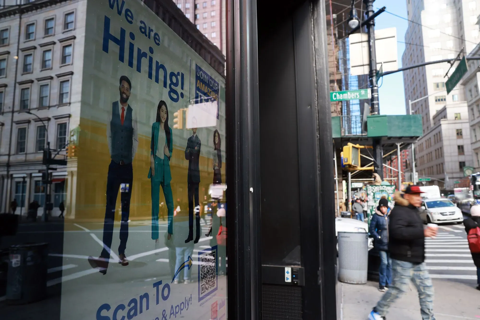 إعلان توظيف يعرض مجموعة من الأشخاص في ملابس رسمية، مع نص "نحن نوظف!"، في شارع مزدحم بمدينة نيويورك.