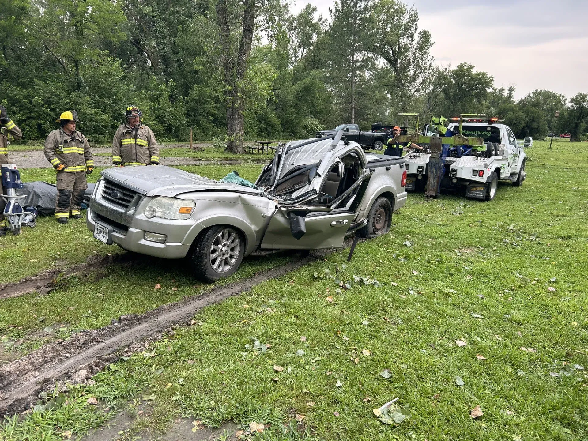 سيارة محطمة في متنزه تو ريفرز بولاية نبراسكا، حيث تضررت جراء عاصفة قوية، مع وجود رجال إطفاء في الخلفية.