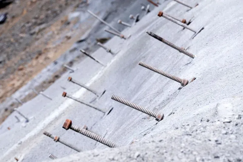 مسامير تربة مدعمة بالفولاذ مثبتة في سطح خرساني، تُظهر جهود إعادة بناء الطريق السريع I-40 بعد إعصار هيلين في نورث كارولينا.