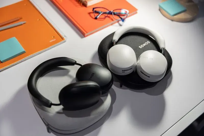 سماعات Sonos الجديدة باللونين الأسود والأبيض موضوعة على طاولة مع أدوات مكتبية، تعكس التحديات التي تواجه الشركة في سوق الصوت المنزلي.