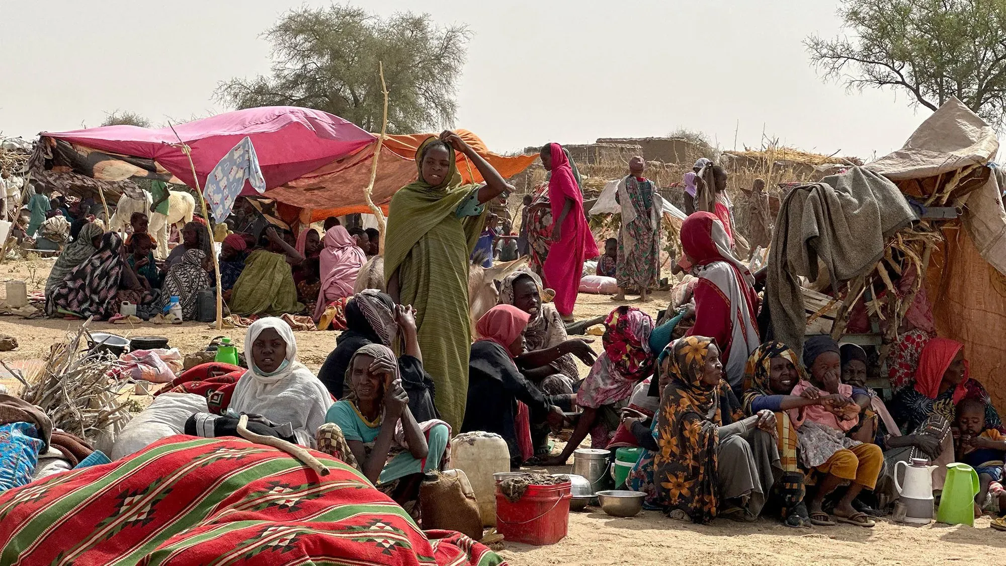 نساء وأطفال نازحون في مخيم زمزم بشمال دارفور، يجلسون وسط ظروف قاسية بعد هجوم قوات الدعم السريع، مما زاد معاناتهم.