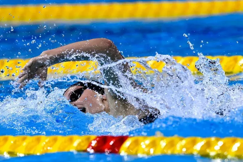 سمر ماكينتوش تسبح بسرعة في سباق 200 متر فردي متنوع، محطمة الرقم القياسي العالمي، مع تناثر المياه حولها في حوض السباحة.