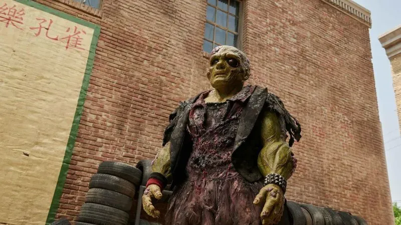 شخصية خيالية مروعة تظهر في بيئة حضرية، ترتدي ملابس ممزقة وتظهر عليها علامات التحلل، مما يثير الفضول حول طبيعة الفيلم.