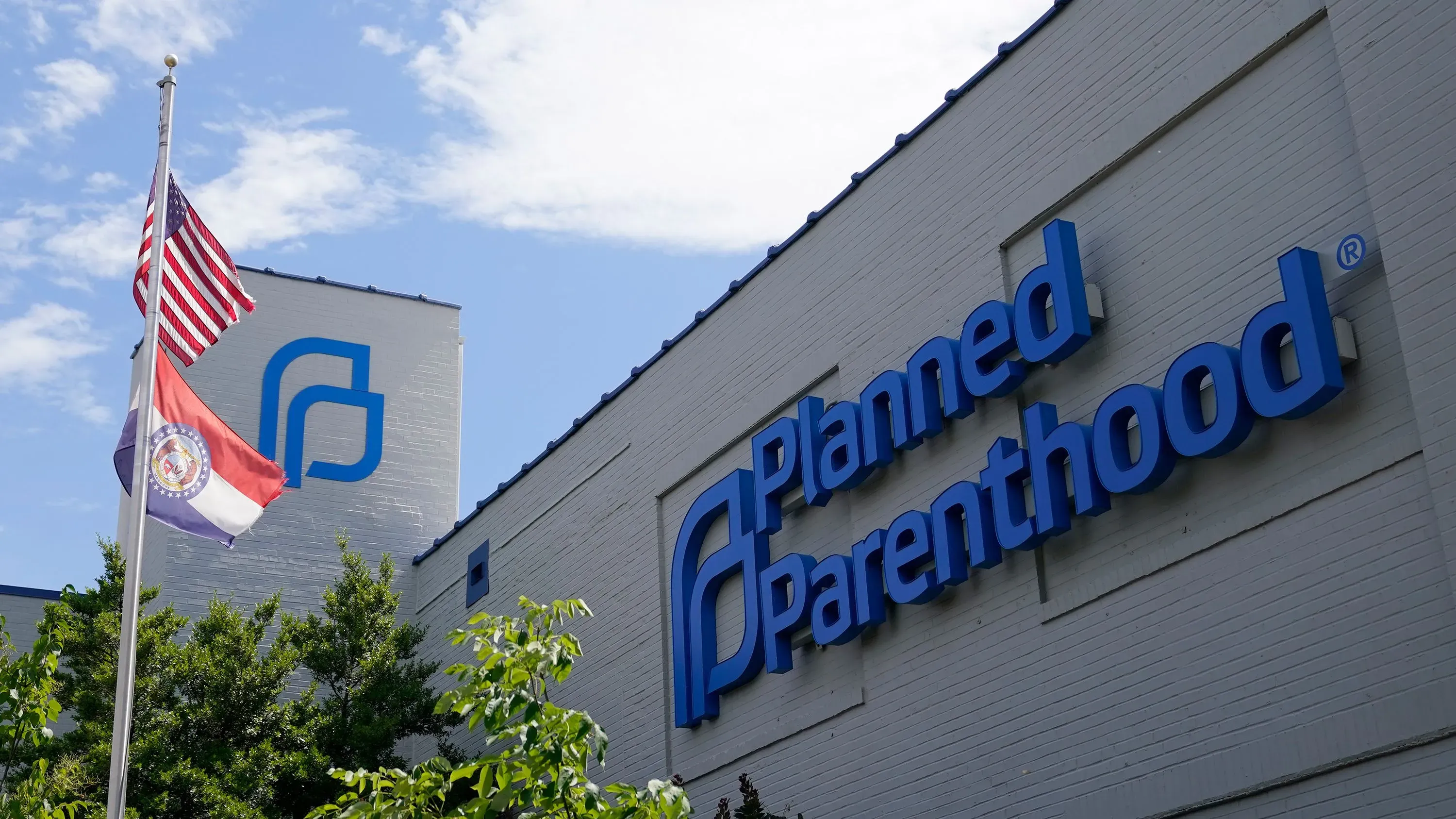 مبنى منظمة "بلانيد باريثود" يبرز في الصورة، مع العلم الأمريكي وعلم ولاية ميسوري يرفرفان أمامه، مما يعكس النقاش حول تمويل الرعاية الصحية.