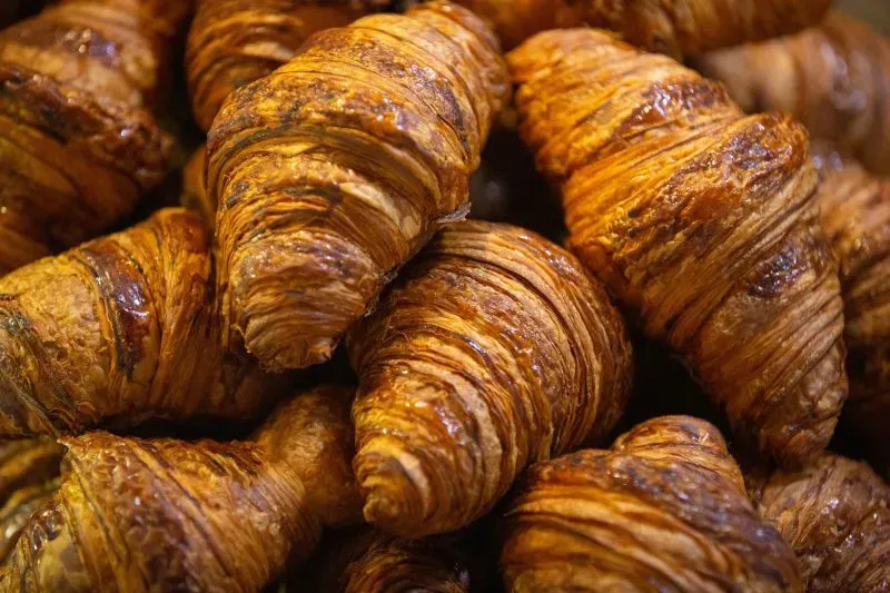 كرواسون ذهبي اللون ومقرمش، مكدس بشكل جذاب، يعكس تأثير ارتفاع أسعار البيض على المخابز.