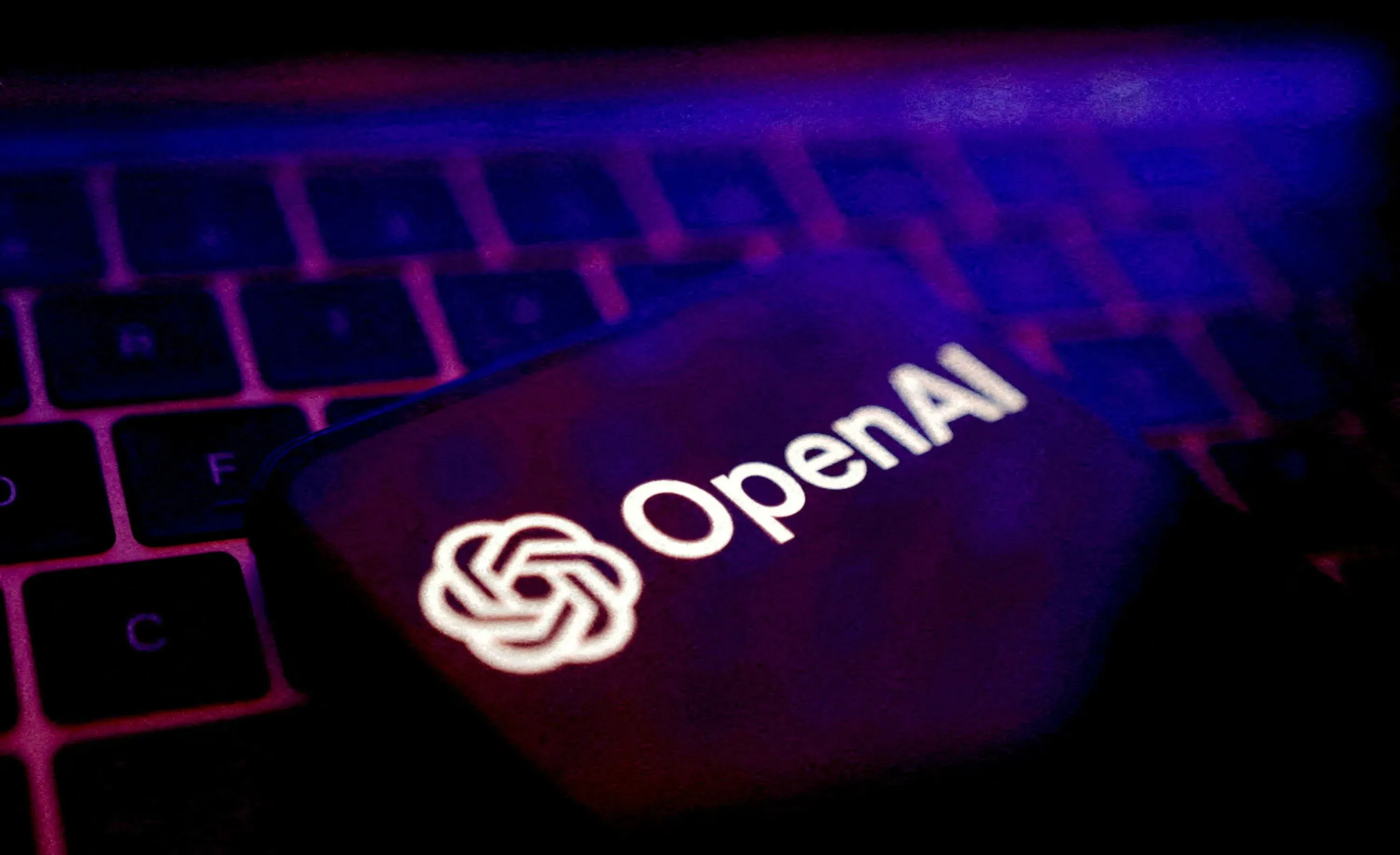 شعار OpenAI مضاء على جهاز كمبيوتر محمول، يعكس تكنولوجيا الذكاء الاصطناعي المستخدمة في مراقبة البيانات وتحليلها.