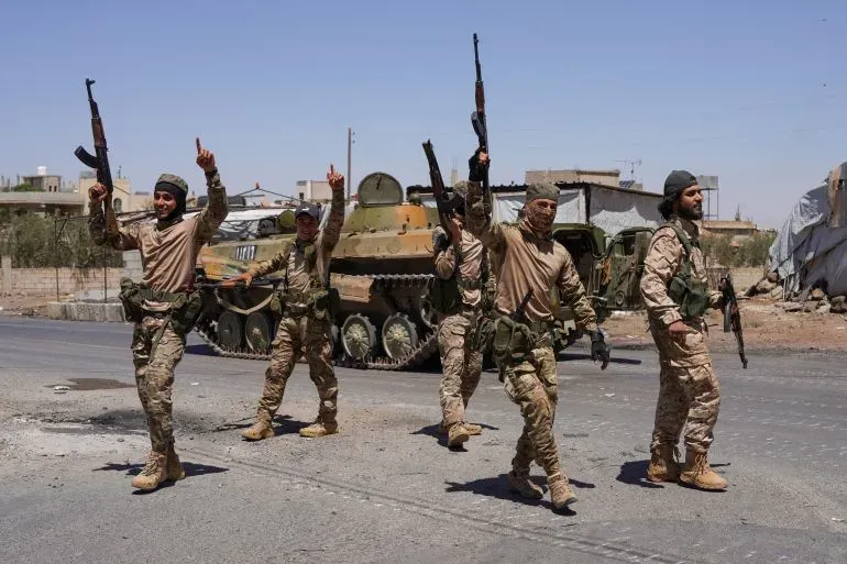 عناصر من قوات الأمن السورية يحملون أسلحة ويحتفلون في محافظة السويداء، مع دبابة في الخلفية، وسط تصاعد التوترات.