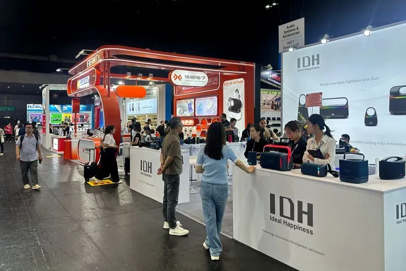 معرض تجاري في هونغ كونغ يعرض منتجات إلكترونية، مع حشود من الزوار يتفاعلون مع العارضين في أجواء حيوية رغم التوترات التجارية.