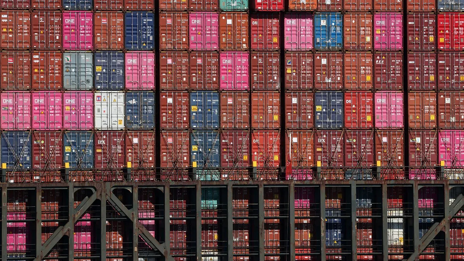 صورة تظهر حاويات شحن ملونة مت stacked في ميناء، تعكس تأثير التعريفات الجمركية على التجارة الأمريكية.