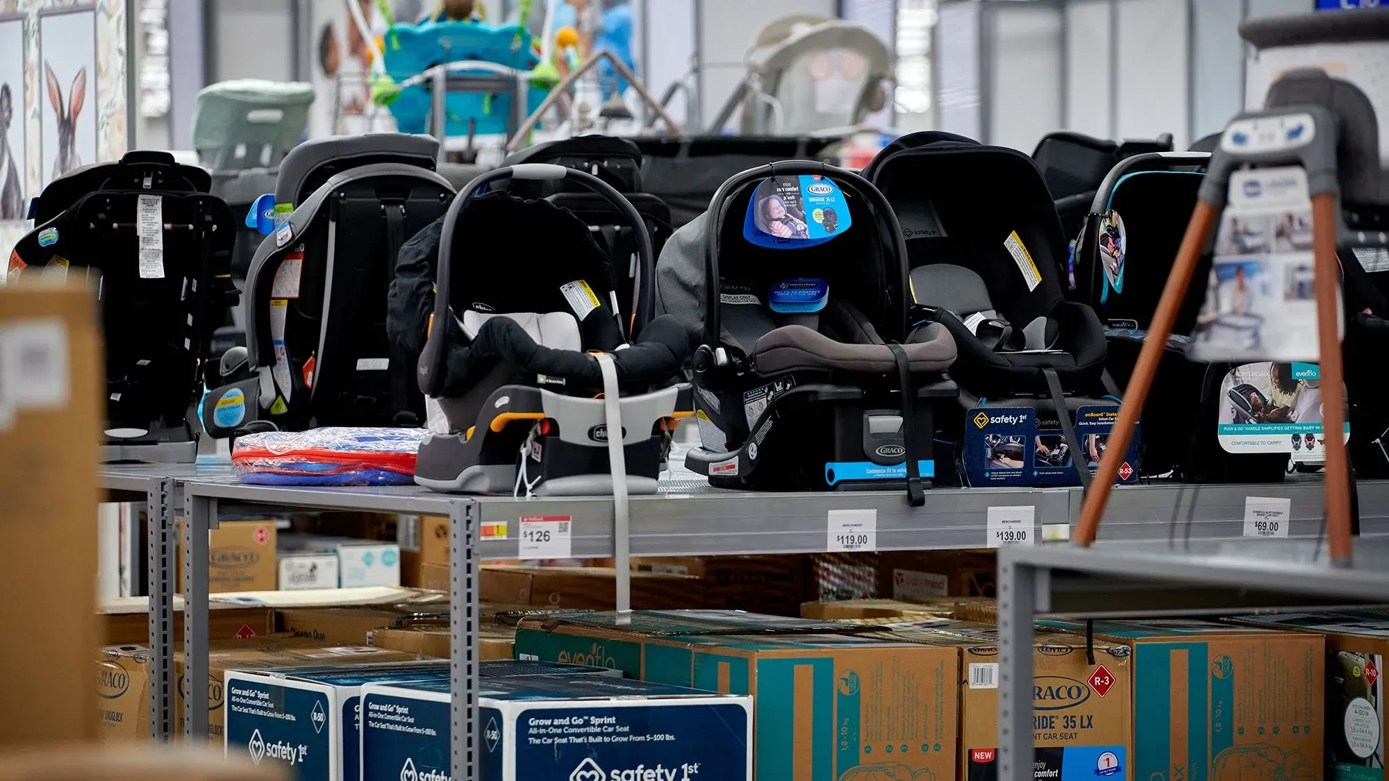 عربات أطفال ومقاعد سيارات مرتبة على رف في متجر لبيع مستلزمات الأطفال، تعكس تأثير التعريفات الجمركية على الأسعار والمخزون.