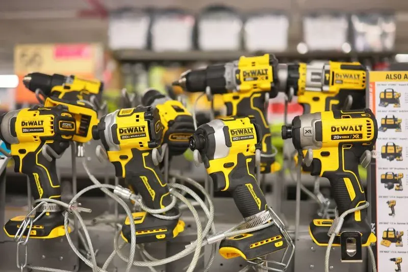 مجموعة من المثاقب الكهربائية من علامة ديوالت، تعرض في متجر، مع التركيز على تأثير الرسوم الجمركية على الأسعار.
