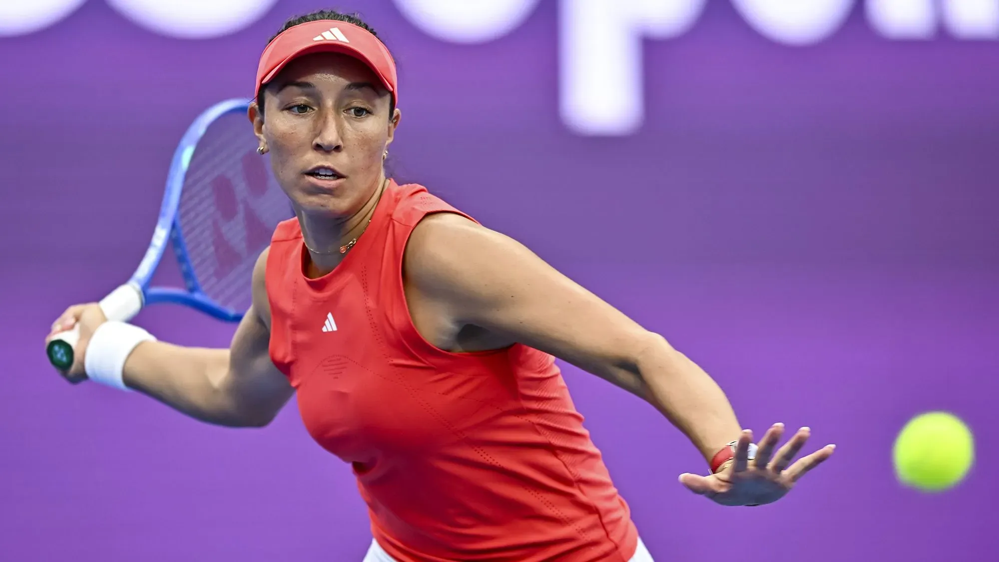 جيسيكا بيجولا، نجمة التنس الأمريكية، في لحظة حماسية خلال مباراة، مع كرة التنس في الهواء، تستعد لضربة قوية.