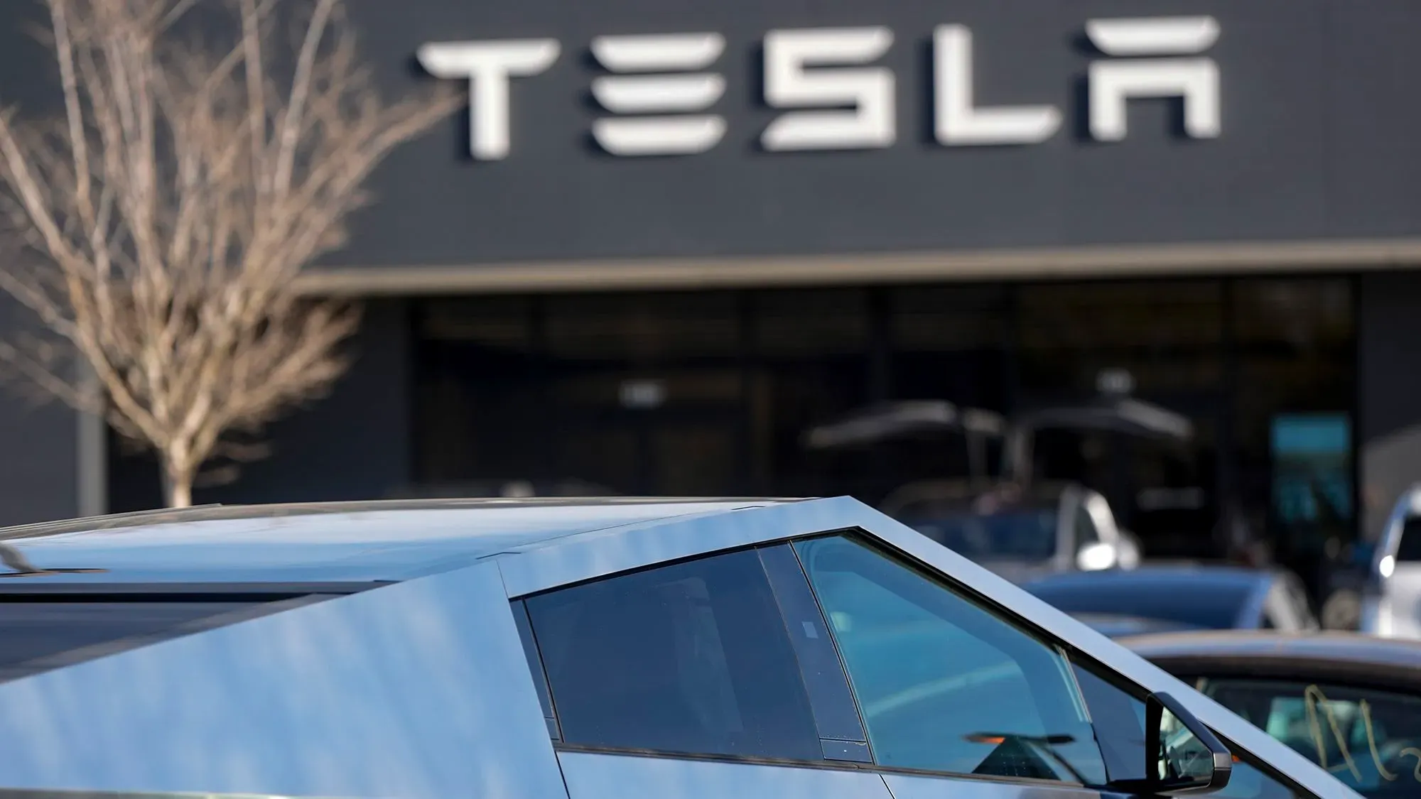 سيارة تسلا الكهربائية معروضة أمام صالة عرض الشركة، حيث تبرز التحديات التي تواجهها تسلا في السوق.