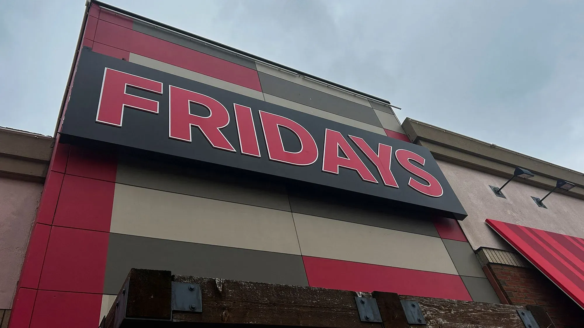 شعار سلسلة مطاعم تي جي آي فرايديز يظهر على واجهة المطعم، مع تصميم عصري يتضمن ألوانًا زاهية، مما يعكس هوية العلامة التجارية.