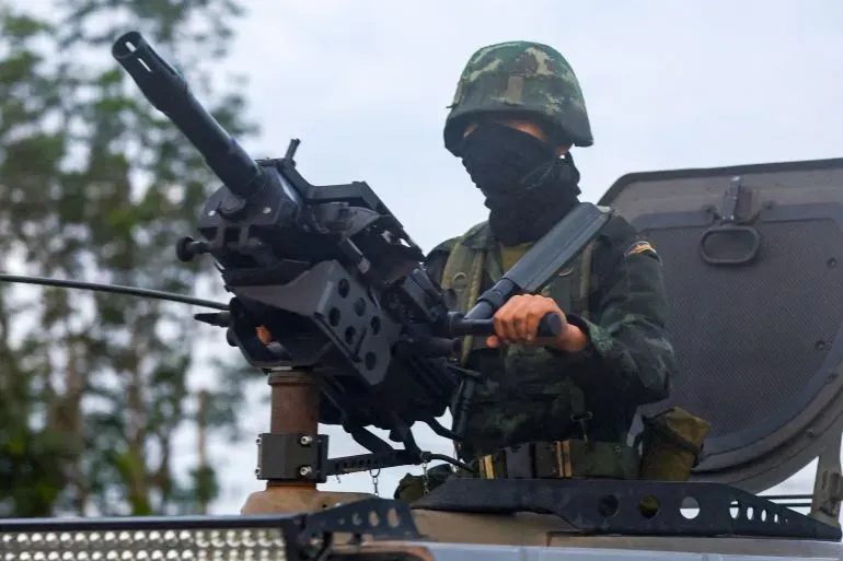 جندي يرتدي قناعًا ويحمل سلاحًا ثقيلًا، يظهر في سياق النزاع الحدودي بين كمبوديا وتايلاند، بعد اتفاق وقف إطلاق النار.