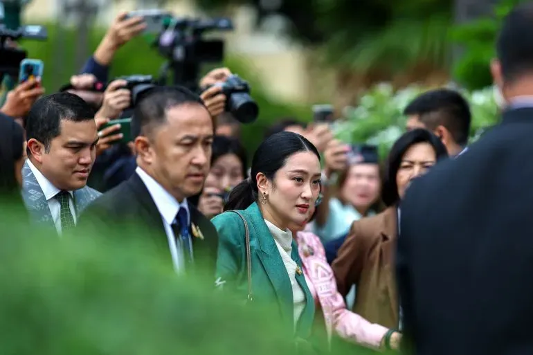 رئيسة وزراء تايلاند بايتونغتارن شيناواترا تتجه نحو المحكمة محاطة بمساعدين وصحفيين، وسط توتر سياسي بسبب اتهامات قانونية.