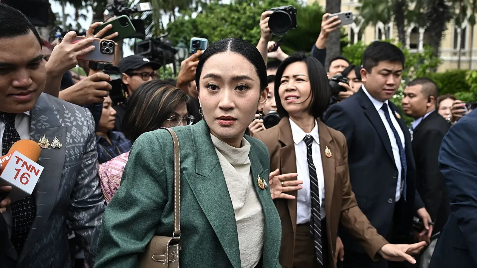 رئيسة وزراء تايلاند بيتونغتارن شيناواترا وسط حشد من الصحفيين والمحتجين، بعد إيقافها عن العمل بسبب تحقيق أخلاقي حول مكالمة مسربة.
