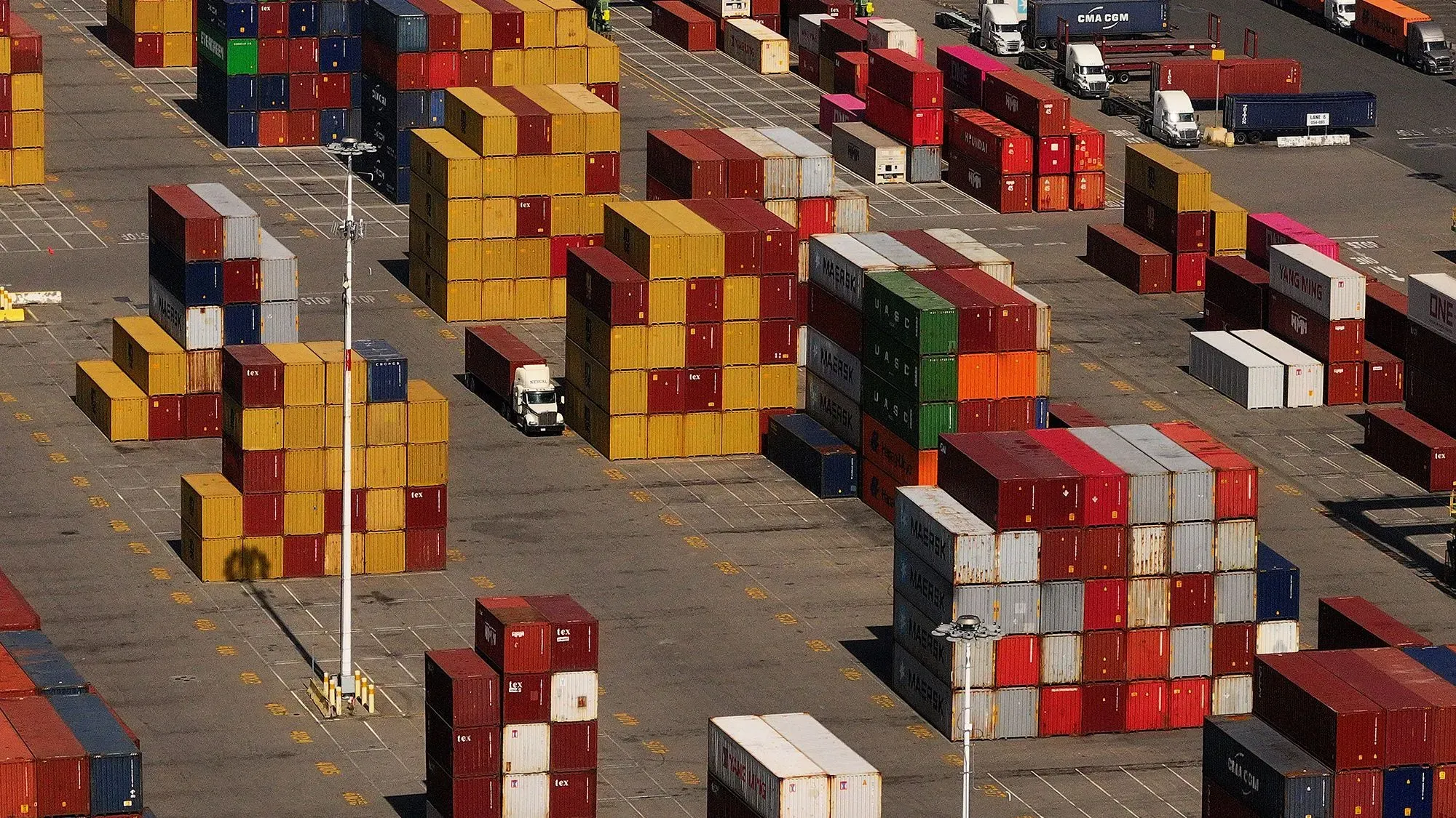 حاويات شحن ملونة مرتبة في ساحة شحن، تعكس تأثير التعريفات الجمركية على التجارة الأمريكية.